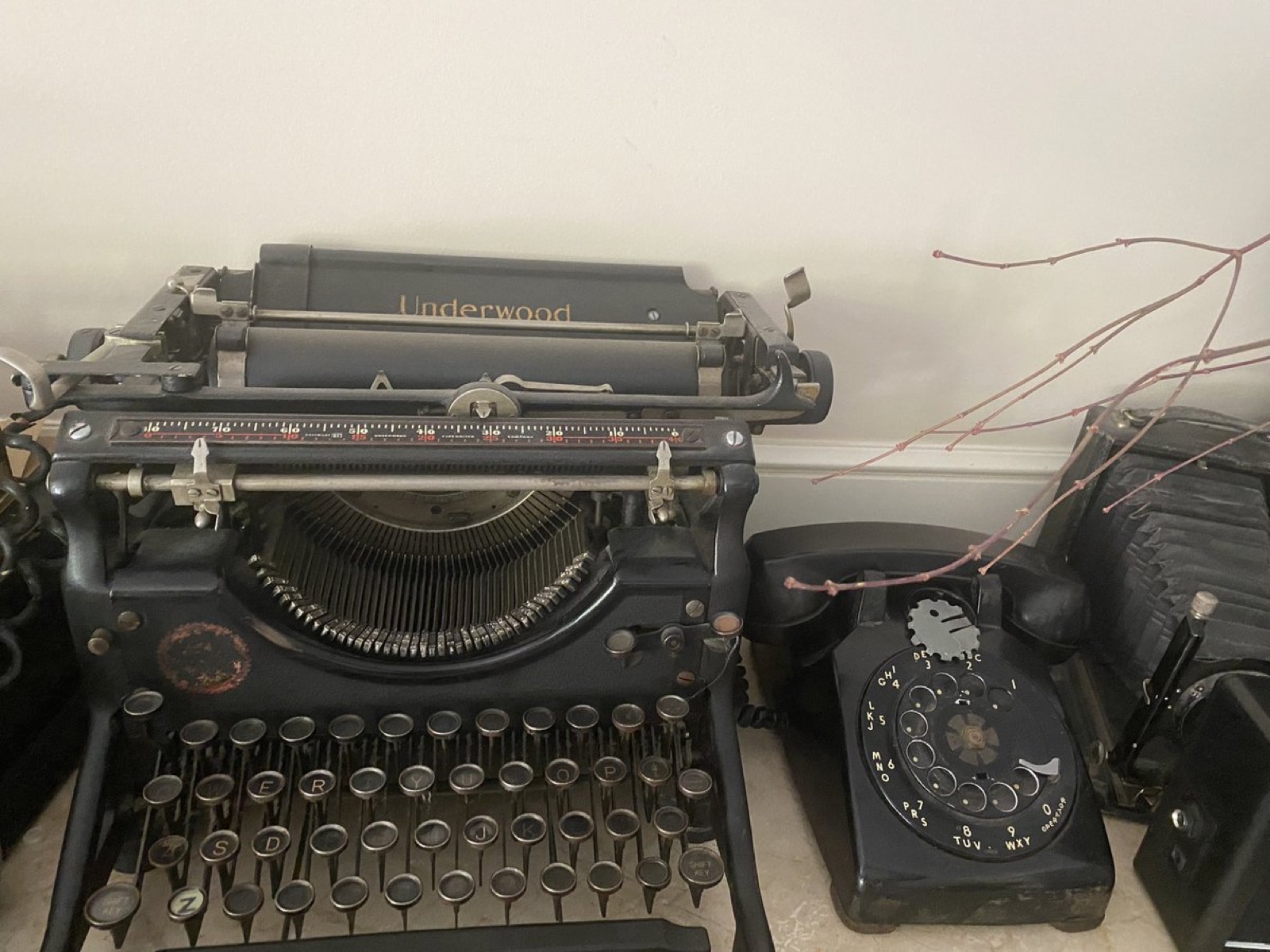 一台黑色的 Underwood 老式英文打字机，旁边是一部黑色的拨盘电话