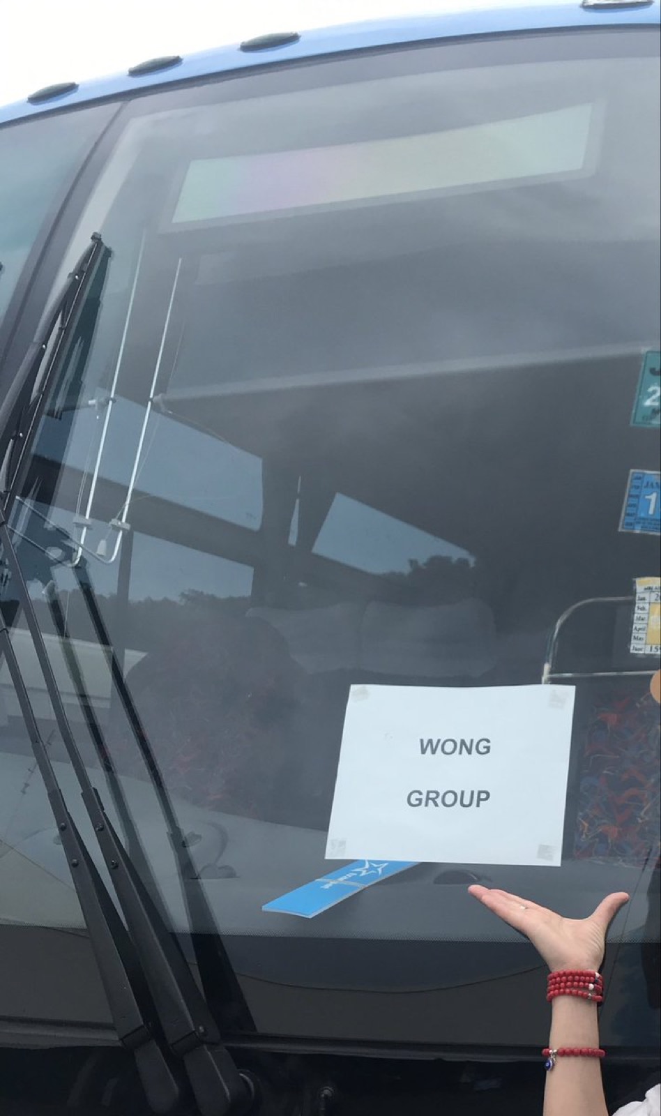 一辆旅游大巴的车窗上贴着写有 WONG GROUP 字样的牌子
