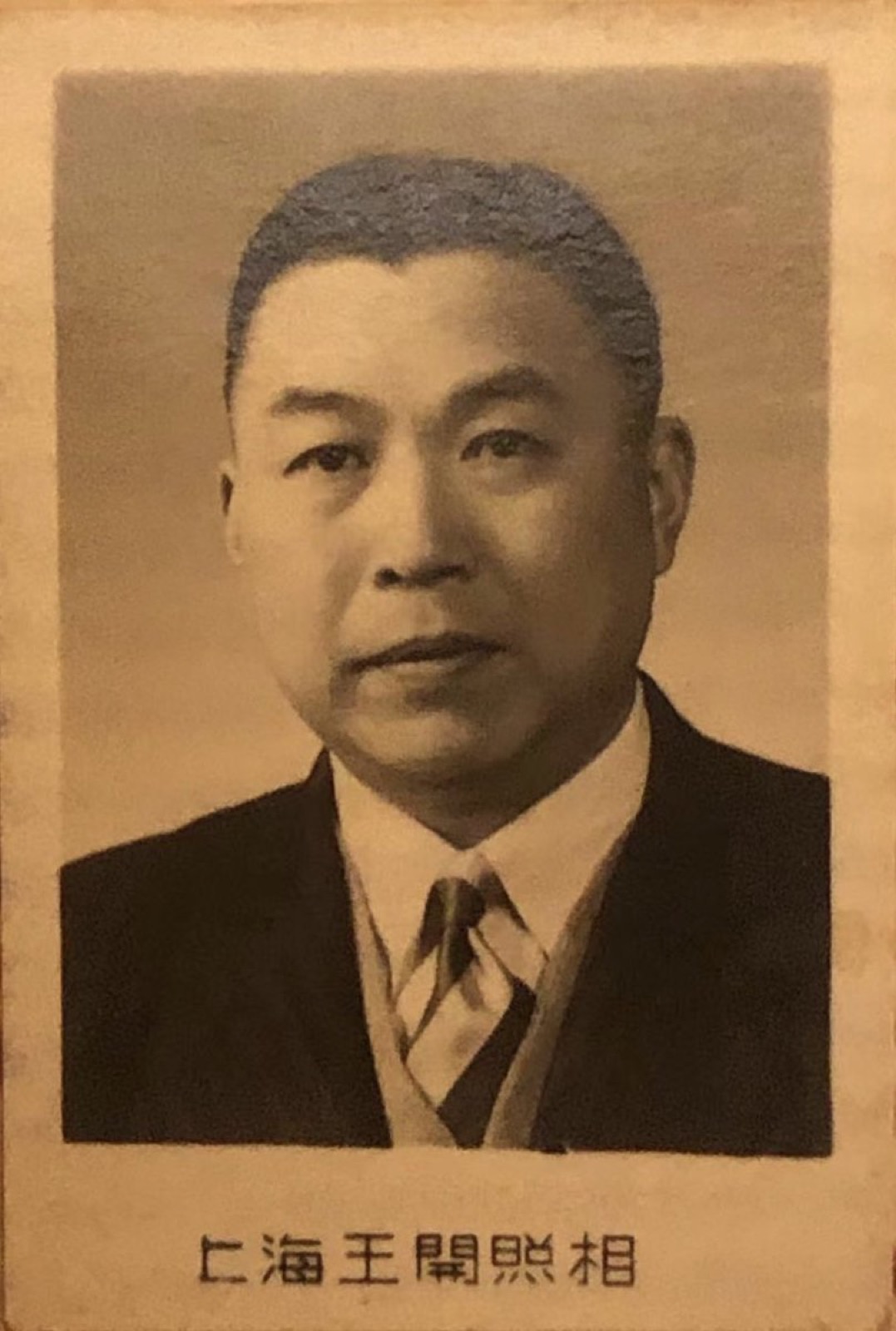 一张泛黄的黑白肖像照，一位穿西装打领带的中年男子，下方印着照相馆的名字