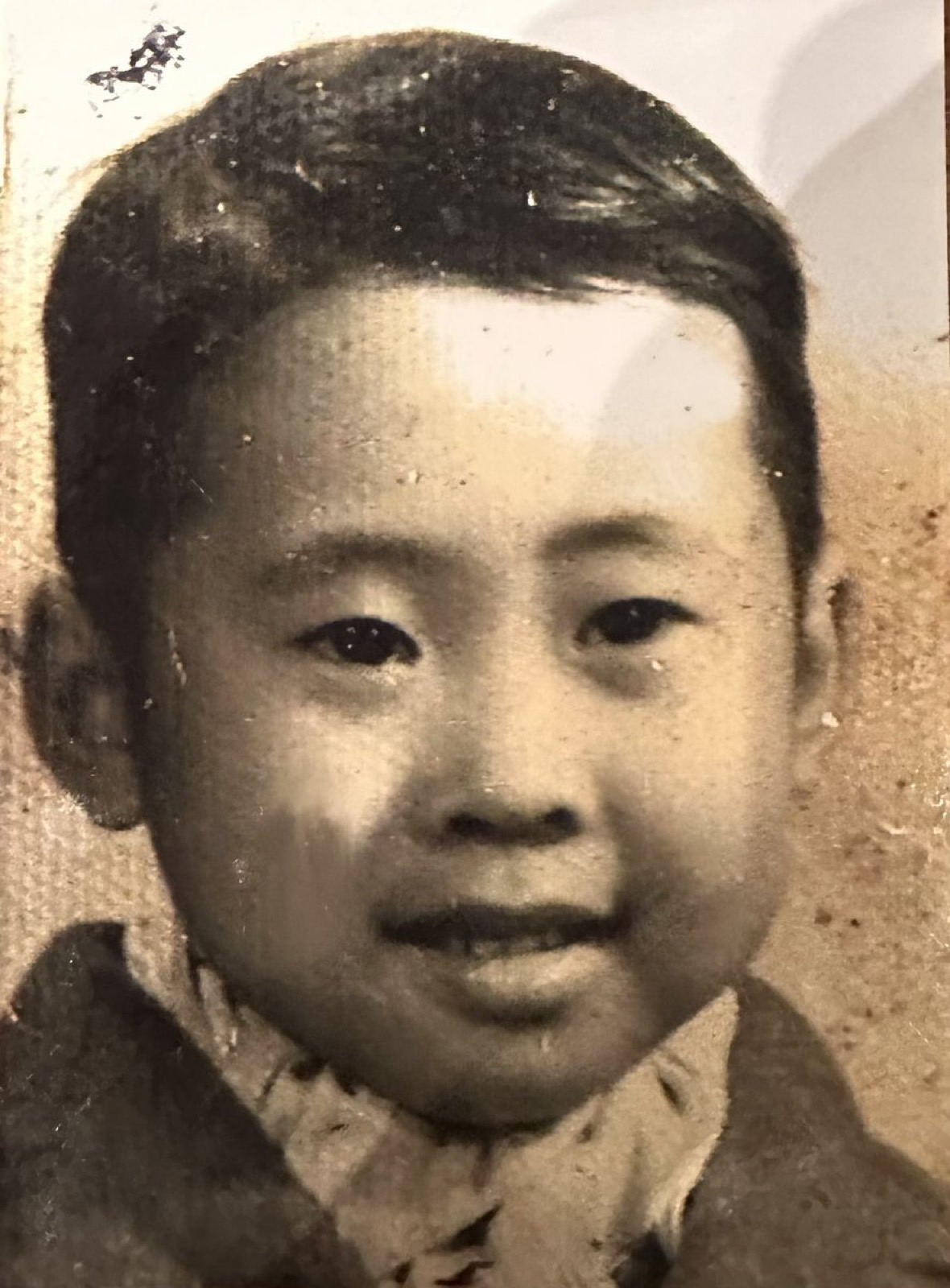 一张发黄的黑白老照片，一个圆脸短发的小男孩