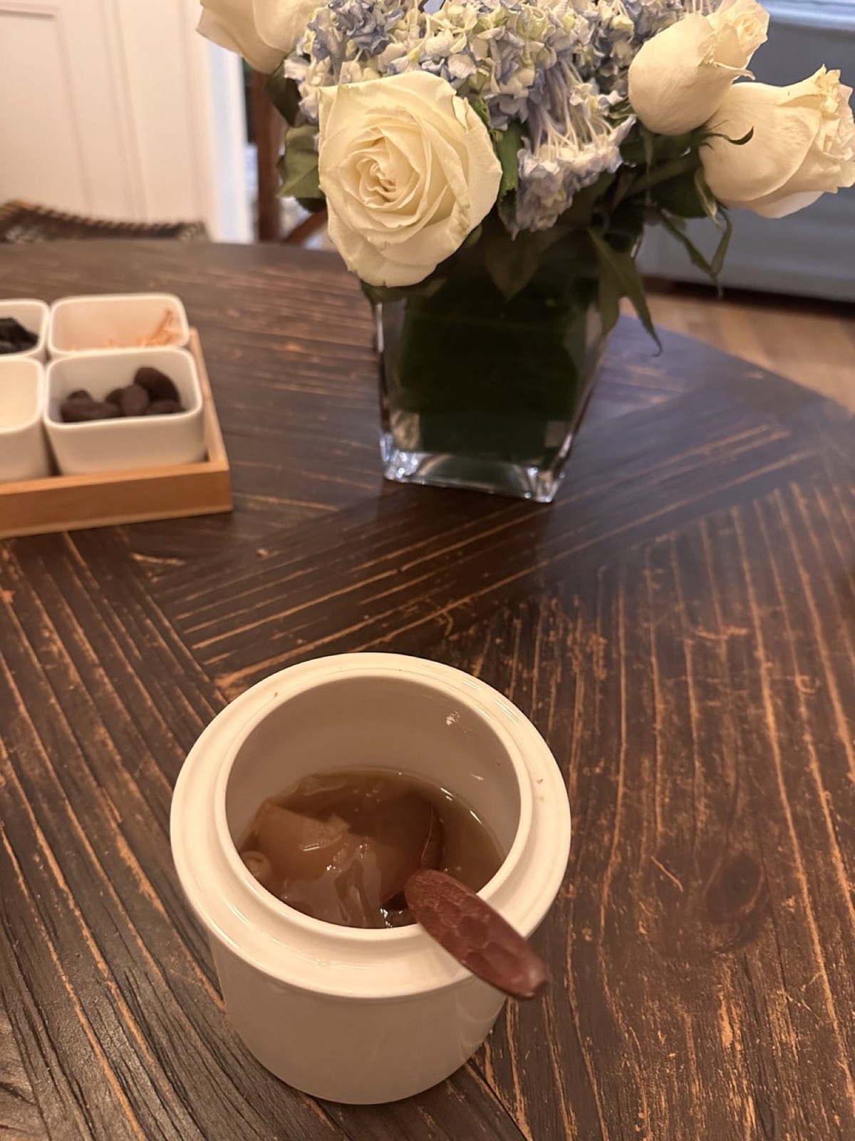 木桌上一盅冰糖银耳雪梨，旁边一瓶白玫瑰和绣球花